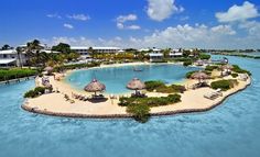 an island with thatched umbrellas in the water