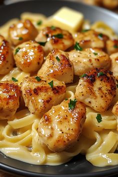 pasta with scallops and cheese on it in a black plate sitting on a wooden table