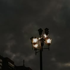 a street light with some lights on it in the dark night sky above tall buildings