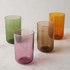 three different colored glasses sitting on top of a white countertop next to each other