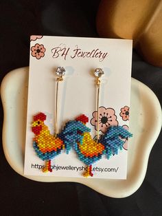 a pair of colorful bird earrings on a white plate