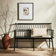 a wooden bench sitting next to a brown vase