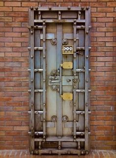 an old metal door in front of a brick wall