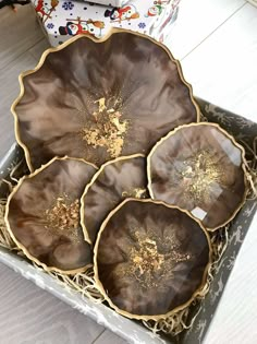 three brown and gold plates in a box on the floor next to a christmas tree