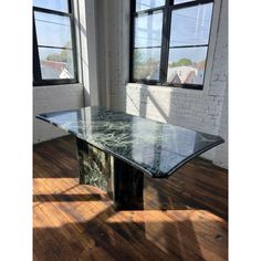 an empty room with two windows and a marble table in the foreground, against a white brick wall