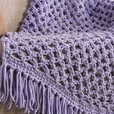 a purple crocheted blanket sitting on top of a couch