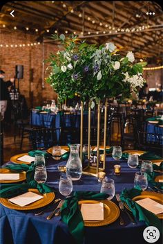 the table is set with blue linens and gold plates, green napkins, and flowers in vases