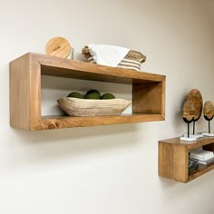 two wooden shelves with bowls and spoons on them against a white wall in a kitchen