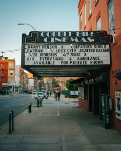 a theater marquee on the side of a street with people walking down it