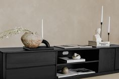 a black entertainment center with candles and vases on the top, along with books