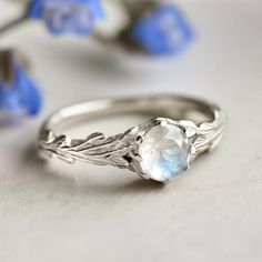 a close up of a ring on a table with blue flowers and leaves around it