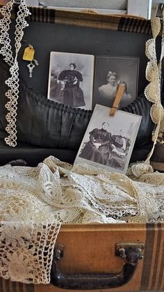 an old suitcase is sitting on the floor with pictures and laces hanging from it