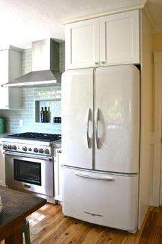 a white refrigerator freezer sitting inside of a kitchen next to a stove top oven