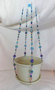 a white pot with beads hanging from it