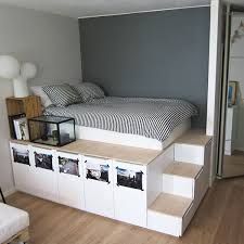 a bed sitting on top of a wooden floor next to a white shelf filled with pictures