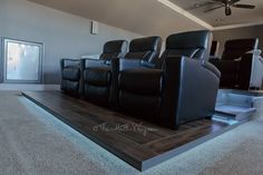 a row of black leather recliners sitting on top of a hard wood floor