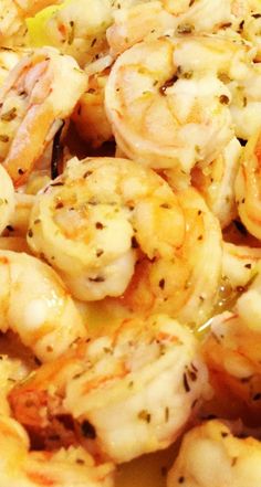 closeup of cooked shrimp on a plate with lemon wedges and seasoning sprinkles