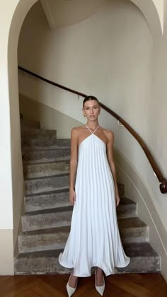 a woman in a white dress standing on some stairs