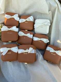 six brown cases with white bows are sitting on the ground next to some grass and flowers