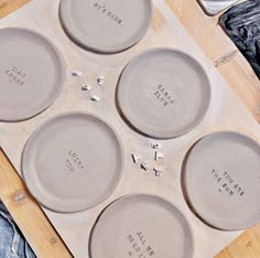 four gray plates sitting on top of a wooden board