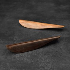 two wooden spoons sitting next to each other on a black surface with dark background