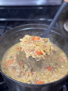 a ladle full of soup is being held over the stove