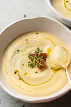 two white bowls filled with soup on top of a table