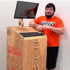 a man standing next to a wooden box with a computer on it