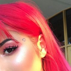 a woman with pink hair and piercings on her ear