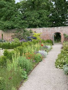 the garden is full of colorful flowers and plants, including an arch in the middle