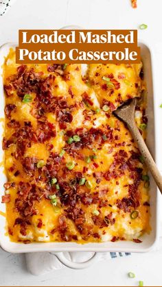 a casserole dish with cheese, bacon and green onions in it next to a wooden spoon