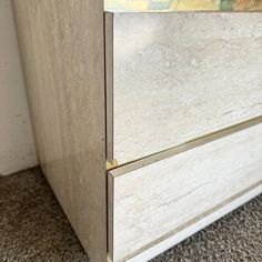 a white cabinet with gold handles on carpeted flooring next to wall and door