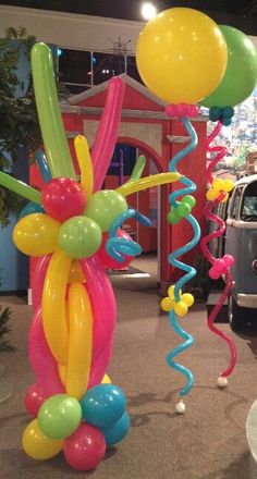 balloons and streamers are hanging from the ceiling in an indoor area with a car