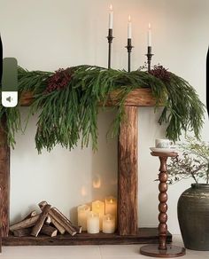 a mantel with candles and greenery on it