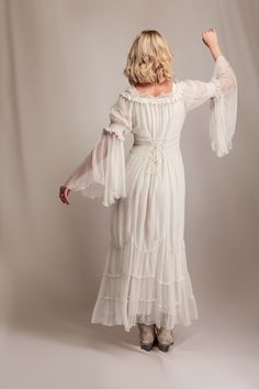 a woman in a white dress is posing for the camera with her arms outstretched and hands behind her back