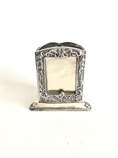 an ornate silver plate with a small square shaped mirror on the front and bottom edge