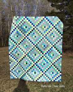 a blue and green quilt hanging from a tree