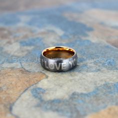 a wedding ring with the word love written on it sitting on a tile floor in front of a wall