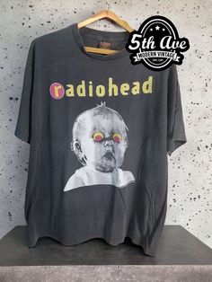 :his vintage-inspired Radiohead t shirt is made from 100% cotton, making it soft, breathable, and comfortable to wear. The black fabric is accented with a bold white print featuring the iconic Pablo Honey Tour logo, which showcases the band's name and tour details in a sleek, minimalist design. The shirt features a classic crew neck and short sleeves, making it a versatile option for any casual occasion. It is expertly crafted with a single stitch construction, creating a clean and streamlined look that is both durable and timeless. This technique involves using a single thread to sew the seams of the shirt, resulting in a smooth finish without any extra bulk or excess fabric. The Radiohead Pablo Honey Tour t shirt is a must-have for any true fan of the band or collector of vintage concert Washed Black Band Merch T-shirt With Graphic Print, Vintage Graphic Print T-shirt For Alternative Fashion, Acid Wash Alternative Style T-shirt With Screen Print, Vintage Short Sleeve T-shirt For Music Festivals, Alternative Style Washed Black Graphic T-shirt, Casual T-shirt For Music Festivals And Alternative Fashion, Alternative Style Washed Black T-shirt With Letter Print, Alternative Washed Black T-shirt With Letter Print, Vintage Washed Black T-shirt For Concert