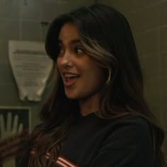 a woman with long hair standing in front of a mirror and smiling at the camera