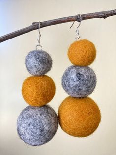 three gray and orange balls hanging from a branch with silver earwires on them