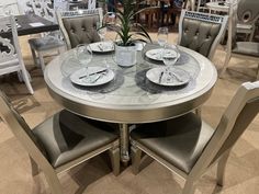 a round table with four chairs and plates on it in a room filled with furniture