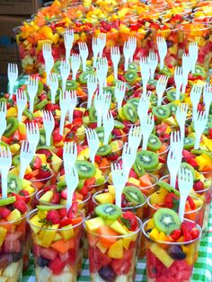 there are many plastic forks in cups filled with fruit