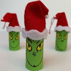 three green bottles with red hats on them and one has an elf's face painted on it