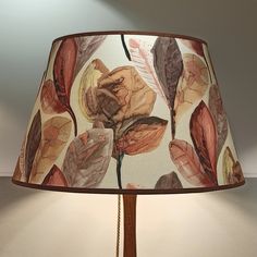 a lamp with a flower print shade on the bottom and brown trim around the lampshade