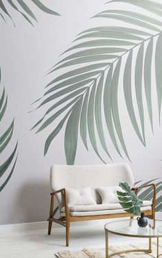 a living room with palm leaves on the wall and a white couch in front of it