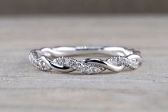 a white gold wedding band with three diamonds on the top and bottom, sitting on a wooden surface