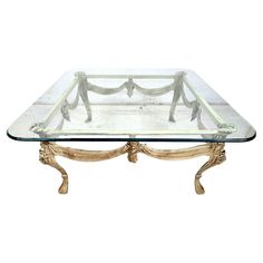 a glass and wood coffee table with an ornate design on the bottom, in gold