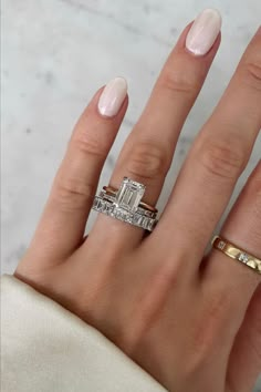 a woman's hand with two different rings on her fingers and one ring in the middle