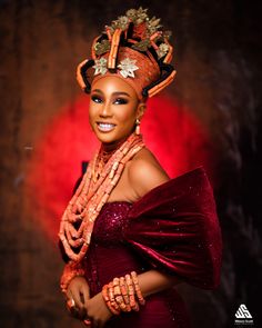 a woman in a red dress and headdress posing for the camera with her hands on her hips